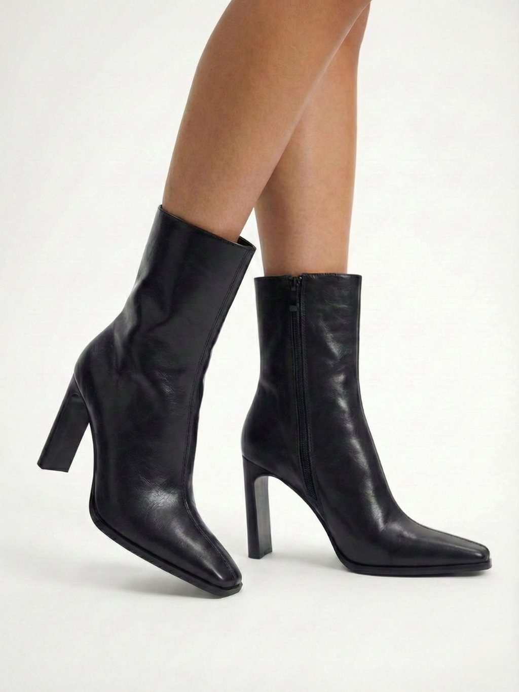 Black high-heel ankle boot with a sleek square toe, smooth leather-look finish, structured shaft, and slim stiletto heel.
