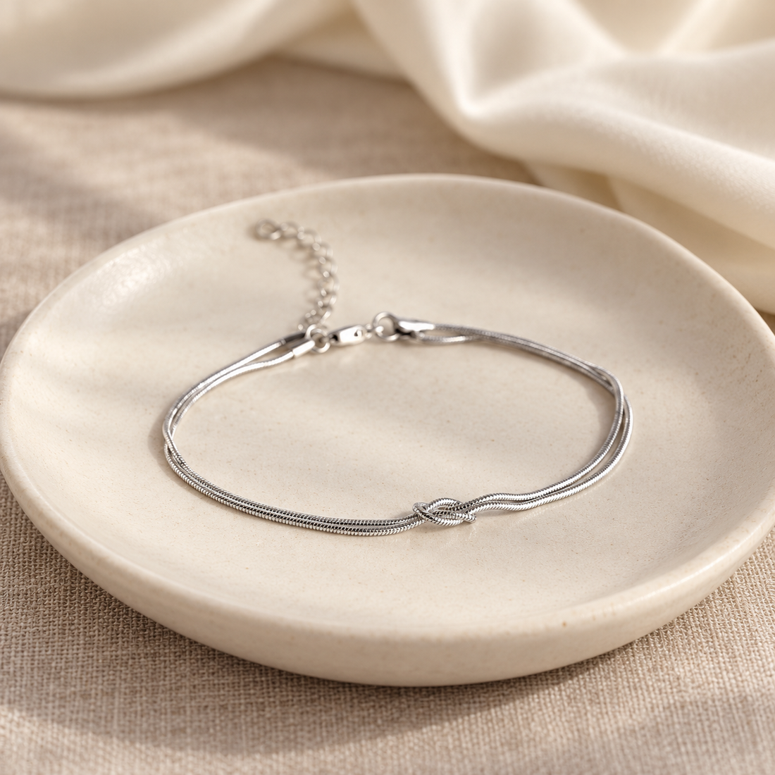 Essential Knot Bracelet in silver on an ivory ceramic dish